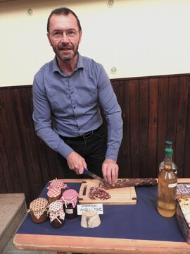 Tone Rozman reže domačo suho salamo, žena Angeli pa je ponudila obiskovalcem okusne piškote.